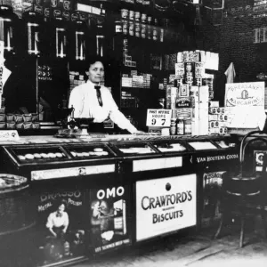 A woman behind the counter of a general store. Cambridge, Cambridgeshire. Circa 1920 A woman behind the counter of a general store. Cambridge, Cambridgeshire. Circa 1920