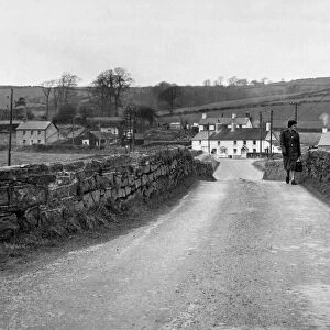 A woman crossing the bridge the village of Llangendeirne in the River Gwendraeth river