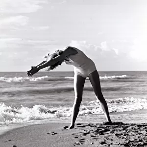 Woman exercising on beach. December 1964 1960s *** Local