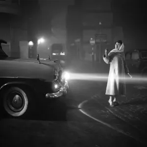 Une femme aidant à diriger le trafic à travers la épaisse brume dans le centre de Londres. Une femme aidant à diriger le trafic à travers la épaisse brume dans le centre de Londres.
