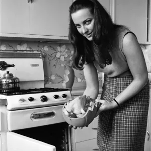 A woman in a kitchen cooking a chicken with a Bobo Pot. 29th March 1967