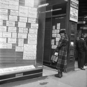 A woman looks in the window of an un-named East End of London employment agency which