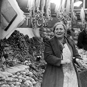 Woman serving on the green grocers stall at Kingston Market. Circa 1936