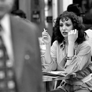 Woman sitting down smoking a cigarette at a cafe in Paris, France