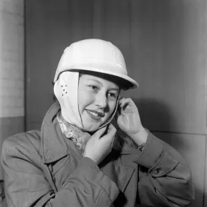 Woman strapping on her crash helmet. October 1952 C5018