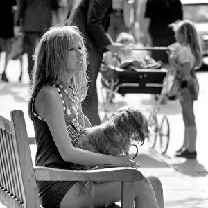 Woman taking her dog for a walk on Kings Road in Chelsea, sitting down on a bench