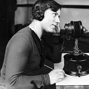 Woman using early telephone. Large candlestick phone Circa 1920