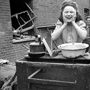 A woman washes her faces surrounded by bomb damage on St