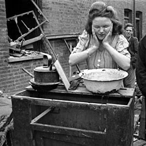 A woman washes her faces surrounded by bomb damage on St