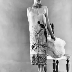 Woman wearing long sleeveless dress with black parrot design at hem Woman wearing long sleeveless dress with black parrot design at hem