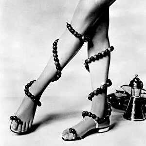 Woman wearing unusual pair of shoes with beads wrapped around her legs