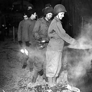 Women of a US Army nursing unit queue up with plates and mugs while camping in Wales to