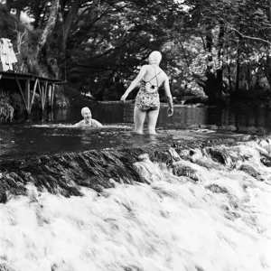 Two women having fun at the top of a waterfall, while on a holiday with Two women having fun at the top of a waterfall, while on a holiday with