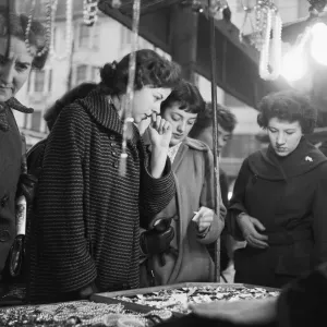 Women peruse the jewellery on a market stall at an un-named street market in the East End