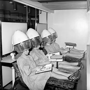 Women reading magazines at the John London Hair and Beauty Saloon whilst under the driers