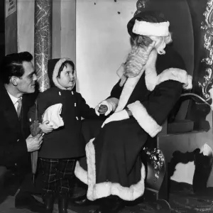 Wonderment in her eyes a young visitor as she gazes up at Santa Claus in Lewis