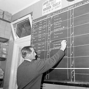 A worker at George Crabbs betting shop in London writing the odds on the chalk board