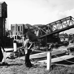 Workman repair the railings on Victoria Dock basin as in the background the new Drypool