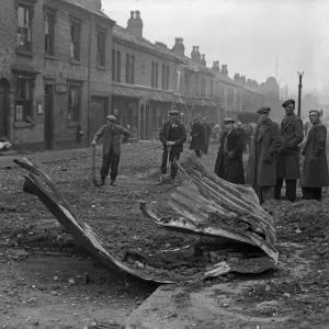 Workmen inspect the remains of a Anderson shelter that was blown over the rooftops into Workmen inspect the remains of a Anderson shelter that was blown over the rooftops into
