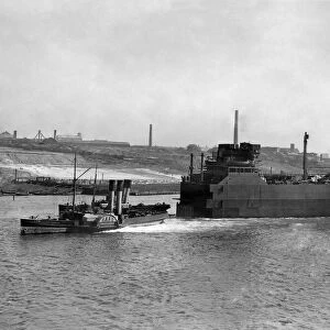 World War II Shipbuilding. Tugs pull The bow Section of a new cargo ship along the river