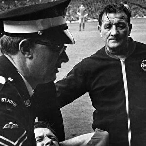 Worried looking Liverpool trainer Bob paisley looks on as Bobby Graham is carried off
