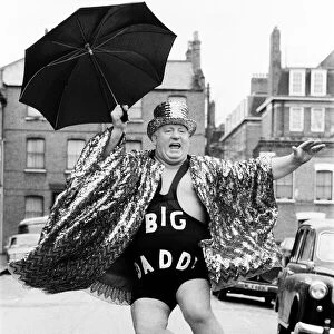 Wrestler Shirley Crabtree alias Big Daddy jumps in the air with an umbrella