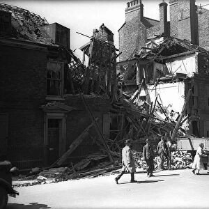 WW2 Bomb Damage in York. People walking past the ruins of a building