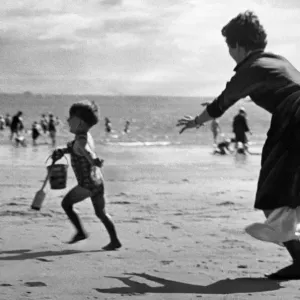 Three year old John Cromwell running away from his mother on the beach at Barry island
