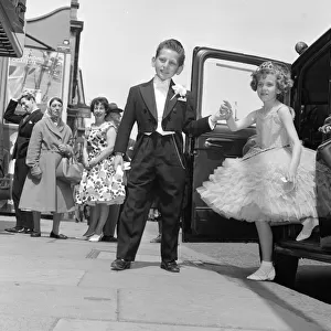 Ten year old Susan Millard wearing a crinoline style ball gown is helped out of her taxi