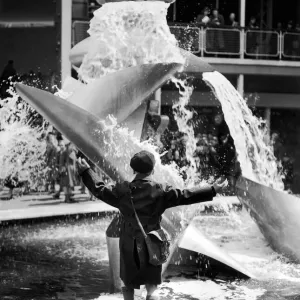 A young boy jumps for joy whilst looking at a modern water feature at the Festival of