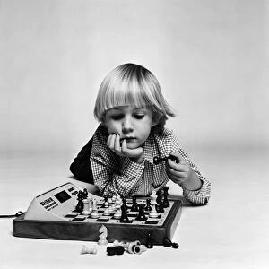 A young boy playing with "Chess Challenger", an electronic chess game