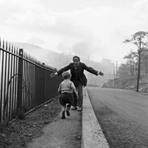 A young boy running into the arms of a man. Ebbw Vale, Blaenau Gwent, Wales