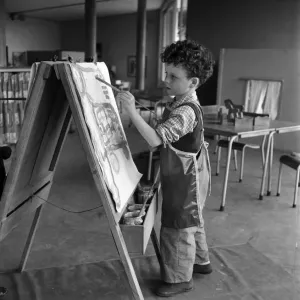 Young boy standing by his easel during an art class at Cookham Nursery School