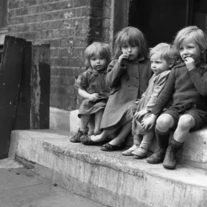 Young children sitting on the doorstep of one of their homes Doris Street, London Young children sitting on the doorstep of one of their homes Doris Street, London