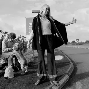 A young couple and their dog trying to hitch hike and get a lift on the motorway A young couple and their dog trying to hitch hike and get a lift on the motorway