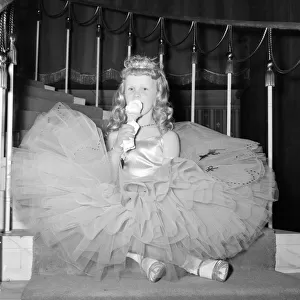 A young girl in her crinoline style ball gown takes an ice cream break during the Junior