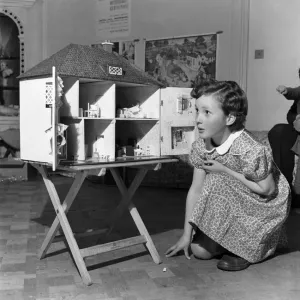 Young girl playing with dolls house. October 1952 C4969