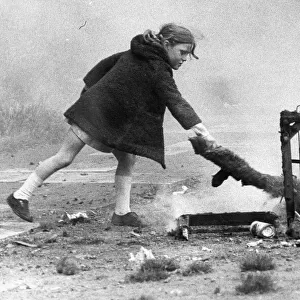 A young girl risks injury playing with fire on wasteland 01 / 11 / 72circa