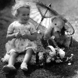 Fille jeune assise dans son jardin arrière protégeant son ours en peluche du soleil sous un parasol. Fille jeune assise dans son jardin arrière protégeant son ours en peluche du soleil sous un parasol.