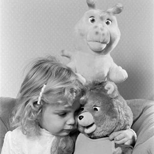 A young girl with soft toys, sitting next to a Teddy Ruxpin toy. 21st October 1986