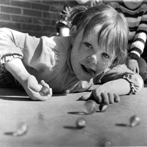 Young girl of Springfield Primary School in Belfast, playing a game of marbles with her