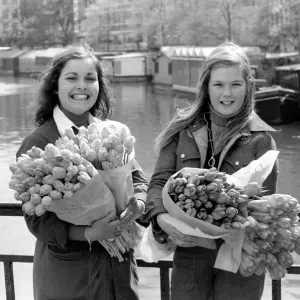 Two young girls of Amsterdam holding bunches of tulips during the season May 1975