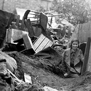 A young lady emerges from an Anderson Shelter after an air raid