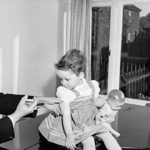 A young patient looks on with trepidation whilst having her polio vaccination