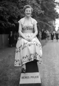 00197 Prints: 1953 Clothing Ascot Fashion Miss Zaila Beckemayel sitting on a police sign laughing