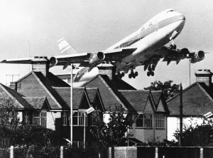 Pollution Prints: 1971 EL AL Boeing 747 taking off over roof tops near London Heathrow Airport