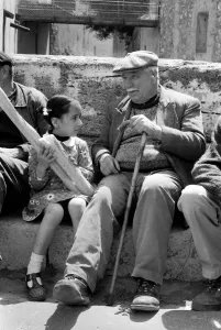 Walking Stick Prints: 6 year old Nathalie Rustan with her French loaves of bread talks to pensioner Michel
