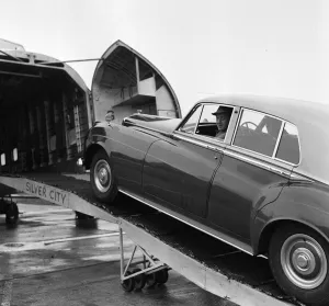 Actor Alec Guinness loading his Bently onto an aircraft bound for France where he will