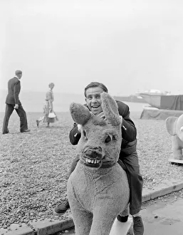 Content Prints: Actor and comedian Norman Wisdom photographed on Brighton Beach on a stuffed donkey