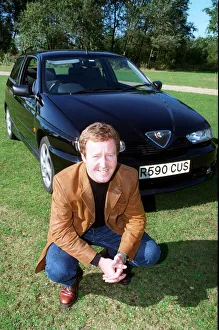 Actor Jonathan Watson September 1997 after testing ALFA ROMEO 145 kneeling in front of